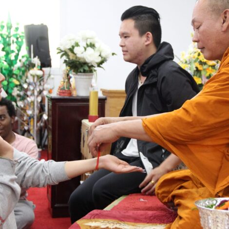 Monk at Hindu temple ties bracelet on students arm